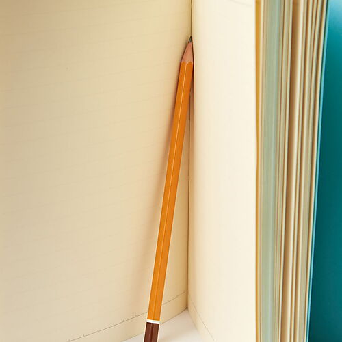 Die „Blauen Bücher“ als tragbares Archiv Aufgeschlagenes helles Notizbuch mit blauem Einband und einem gelben Bleistift zwischen den noch unbeschriebenen Seiten.