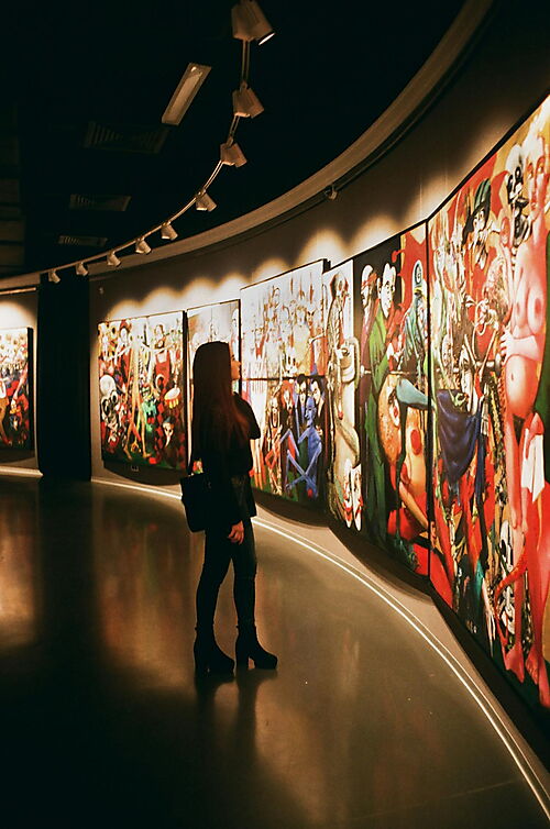 Junge Frau betrachtet Bilder in einer Kunstausstellung