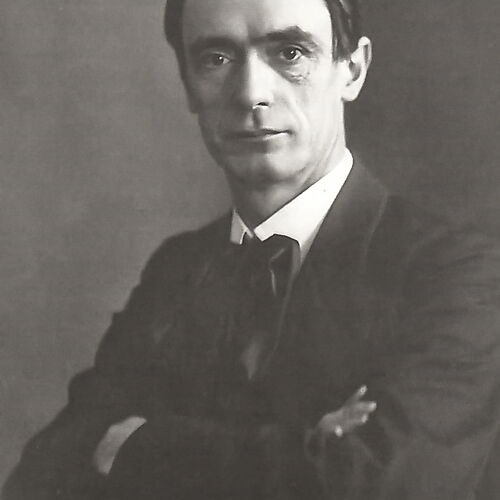Rudolf Steiner um 1905 Schwarzweißporträt Rudolf Steiners um 1905; er sitzt im dunklen Anzug mit verschränkten Armen und blickt in die Kamera.