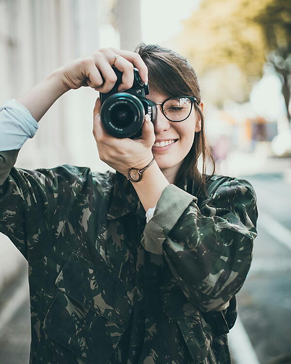 Frau fotografiert mit einer DSLR-Kamera – Symbolbild für Fotoauswahl und Vorbereitung, um typische Fehler bei Malen-nach-Zahlen-Foto-Sets zu vermeiden.