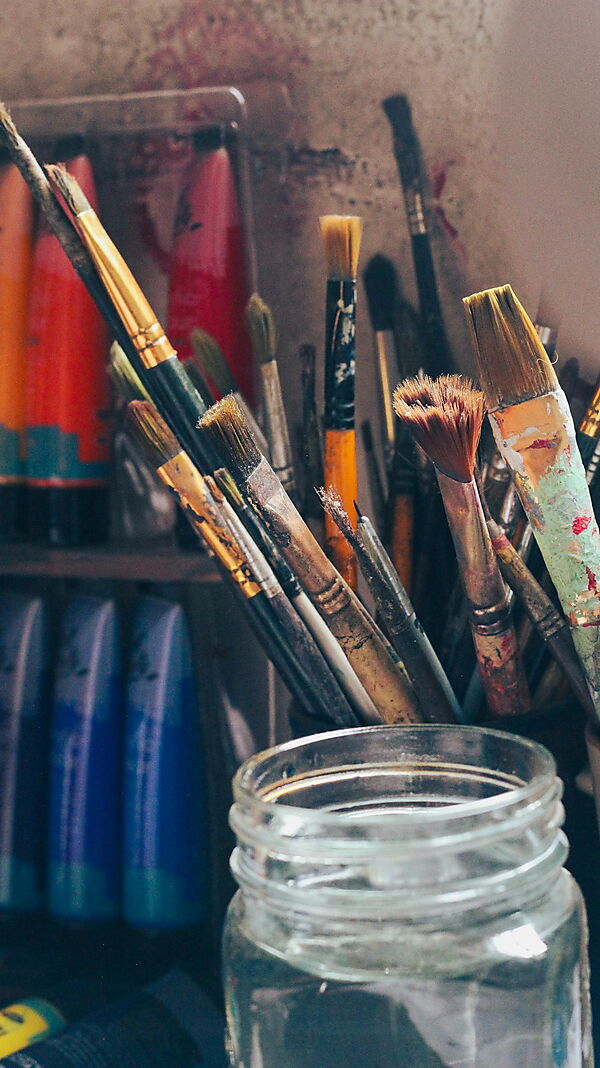 Pinsel, Acrylfarben und Malzubehör auf einem kreativen Arbeitsplatz als Einstieg in Material und Setup der Acrylmalerei.