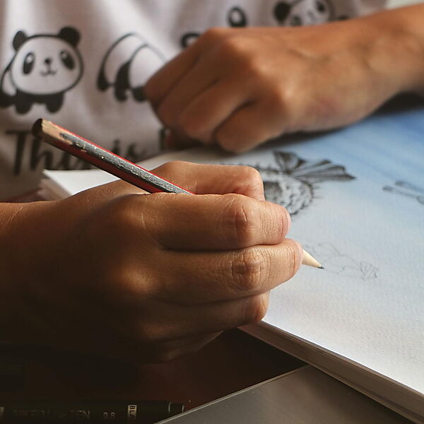Hand zeichnet mit Bleistift in ein Skizzenbuch und übt eine detaillierte Skizze.