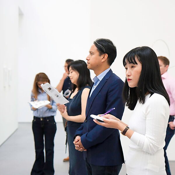Mehrere Menschen betrachten gemeinsam Kunstwerke in einem modernen Museum.
