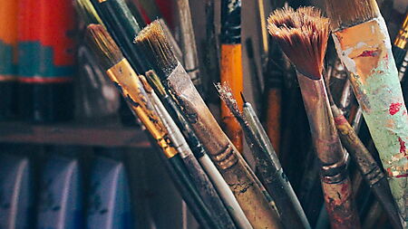 Pinsel, Acrylfarben und Malzubehör auf einem kreativen Arbeitsplatz als Einstieg in Material und Setup der Acrylmalerei.