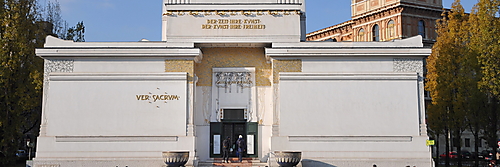 Frontansicht des weißen Gebäudes der Wiener Secession mit symmetrischer Fassade, vergoldeter Lorbeerkuppel und dem Wahlspruch über dem Eingang.